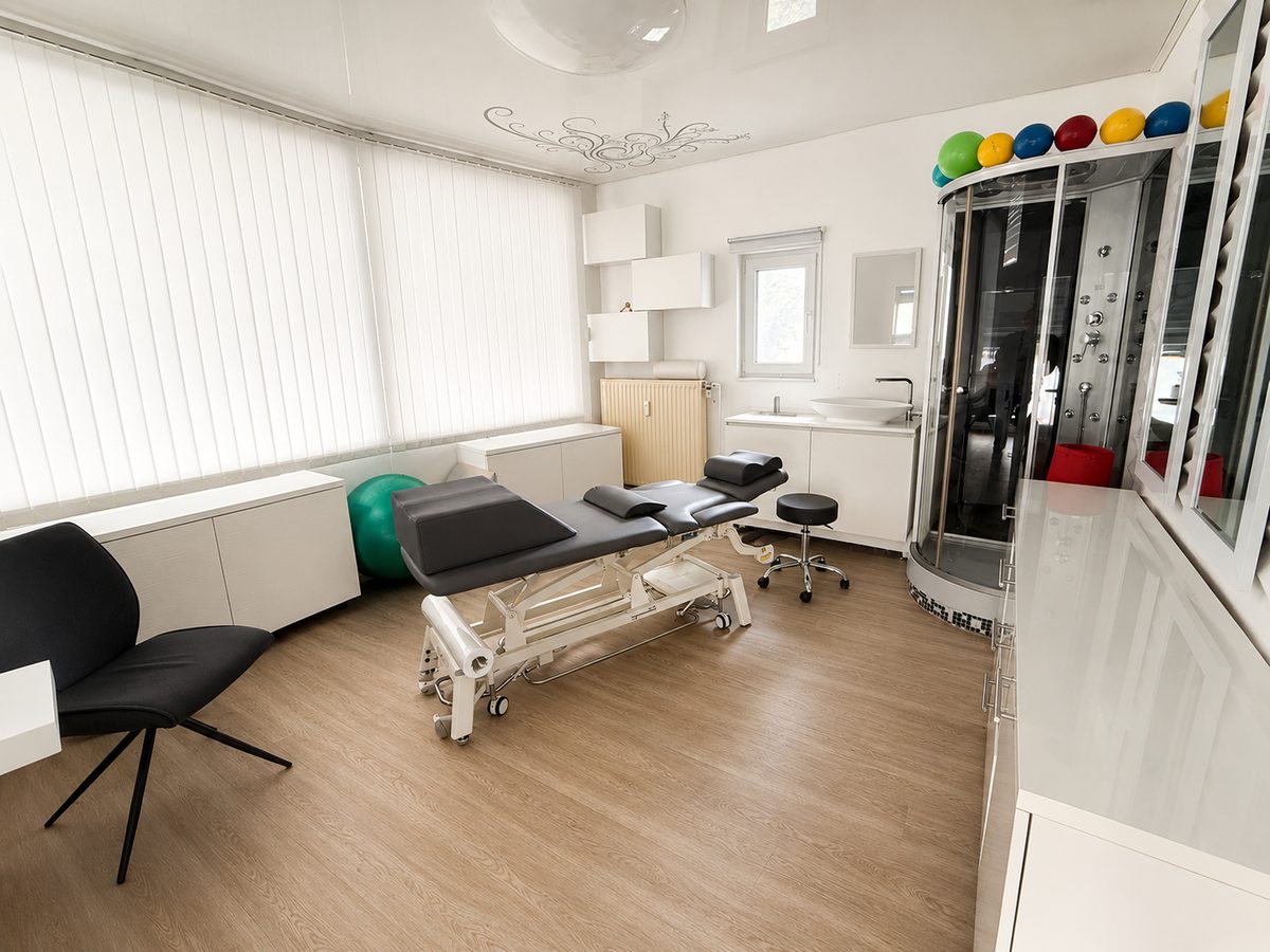 Behandlungsraum der Praxis mit Liege, Gymnastikbällen und Trainingsgeräten