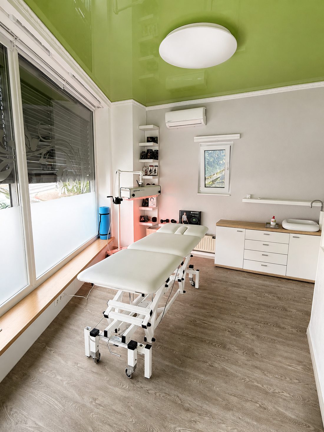 Behandlungsraum der Physiotherapie Mutić in Gelnhausen: höhenverstellbare Liege vor einem großen Fenster